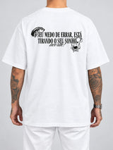 Cor: Branco | Costas | Oversized — Camiseta Seu Medo de Errar Está Tirando o Seu Sonho, Acorde (Verso)